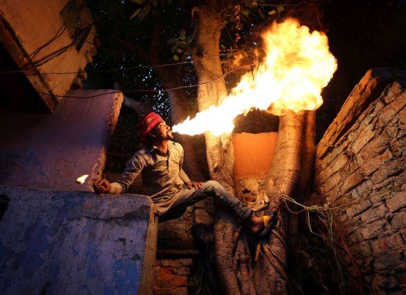 Fire breather Amit Kumar Bhatt practising his craft at his home in the Kathputli slum colony of New Delhi, India, December 10th, 2014. He is one of 40,000 people living in the slum, which is popularly known for being the worlds largest colony of street performers, including magicians, snake charmers, acrobats, singers, dancers, actors, traditional healers and musicians and puppeteers. Their livelihood is under threat however as the Delhi government has obtained contracts to demolish the colony to make way for developers to build high-rise apartments. Photo Credit: Susannah Ireland