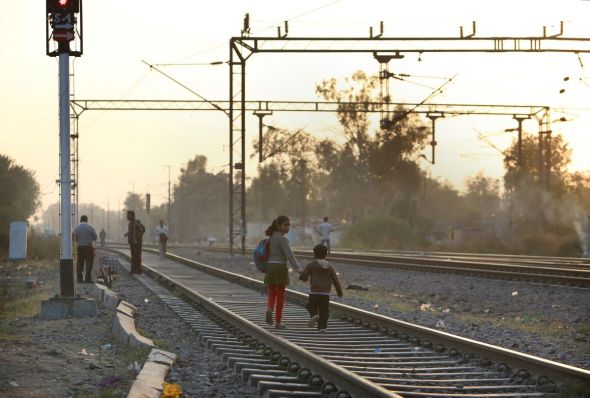 Children walk home on the railway track which runs alongside the Kathputli slum colony of New Delhi, India, December 10th, 2014. 40,000 people live in the slum, speaking 11 different languages, which is popularly known for being the worlds largest colony of street performers, including magicians, snake charmers, acrobats, singers, dancers, actors, traditional healers and musicians and puppeteers. Their livelihood is under threat however as the Delhi government has obtained contracts to demolish the colony to make way for developers to build high-rise apartments. Photo Credit: Susannah Ireland